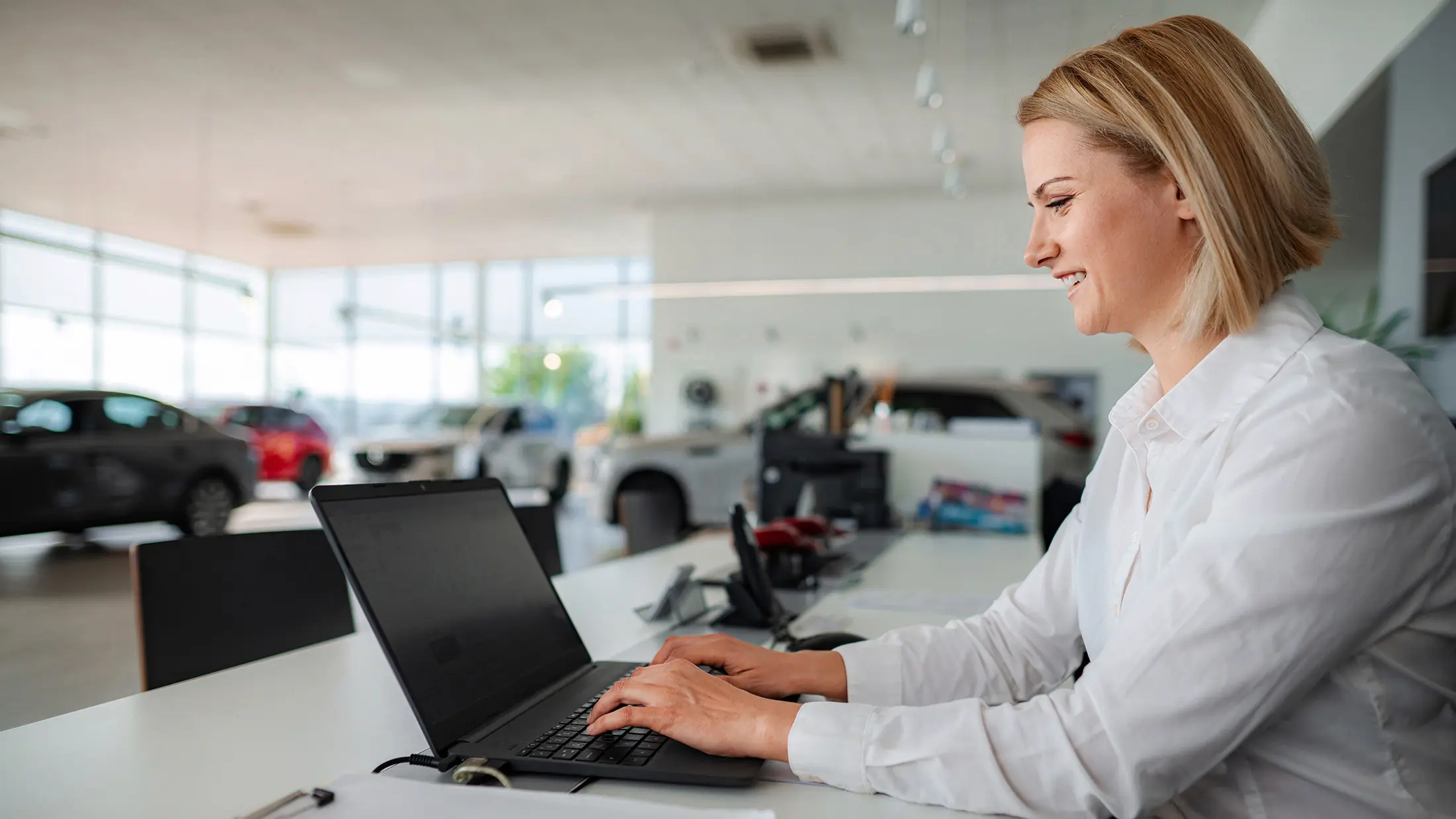 Freundliche Mitarbeiterin an der Serviceannahme eines Autohauses am Schreibtisch